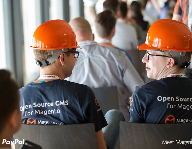 Two men wearing orange hard hats and T-shirts with "Open Source CMS for Magento" branding