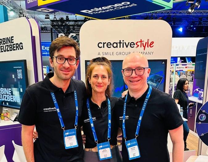 Three team members posing at a creative style trade show booth with Akeneo branding