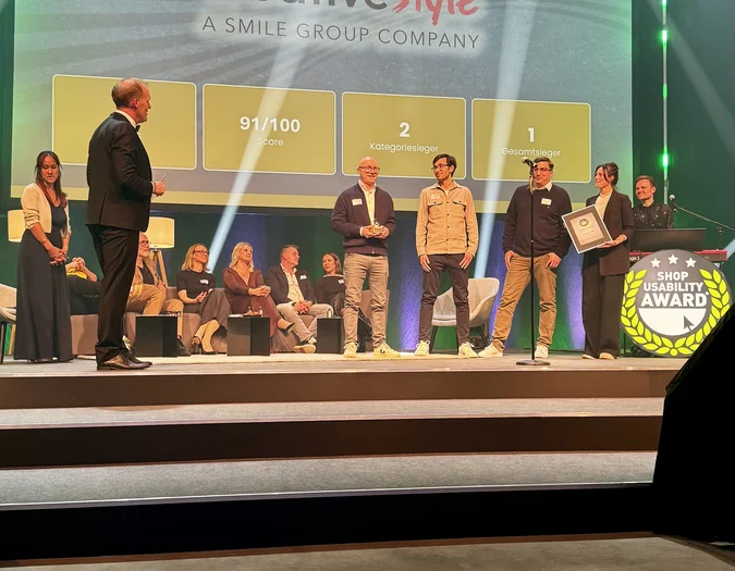People on stage at an award ceremony, "Agentur des Jahres" displayed on a screen, with one person holding a certificate.