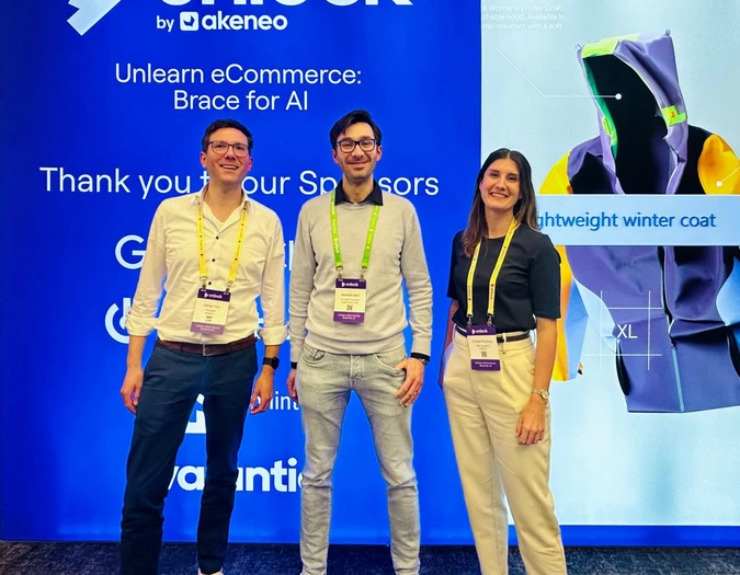 Three team members posing in front of a blue Akeneo unlock event backdrop