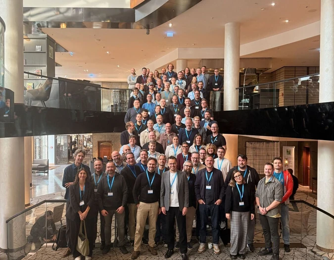 Large group of team members posing for a group photo on a wide staircase in a modern foyer