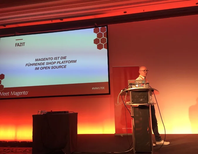 Speaker at a Meet Magento event presenting a slide titled "FAZIT" about Magento as a leading open-source shop platform