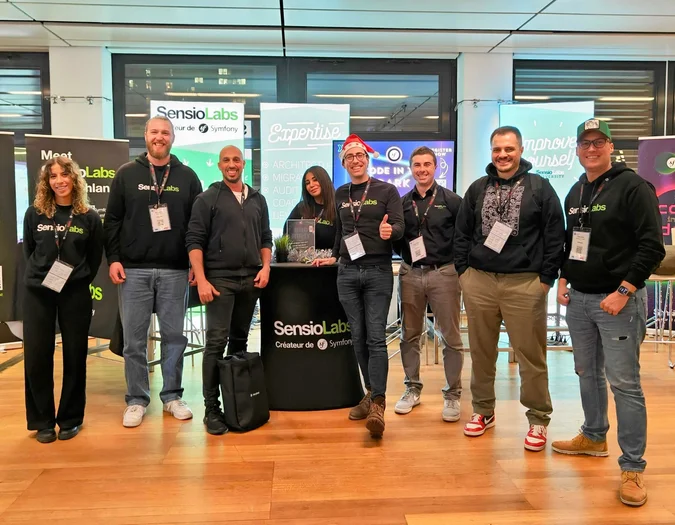 SensioLabs team members posing at a branded event booth with Expertise and Symfony banners