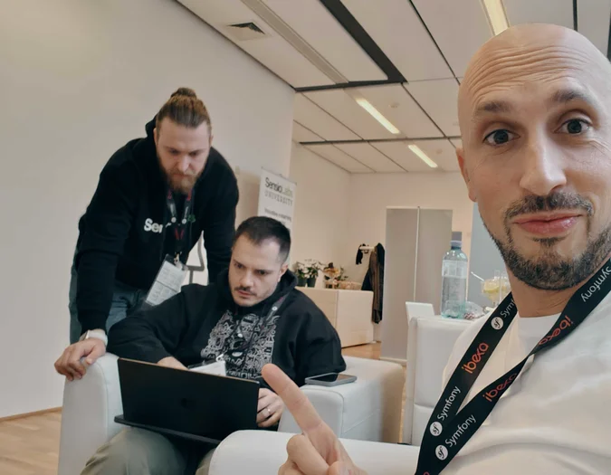 Three men working on laptops in a modern office with SensioLabs branding