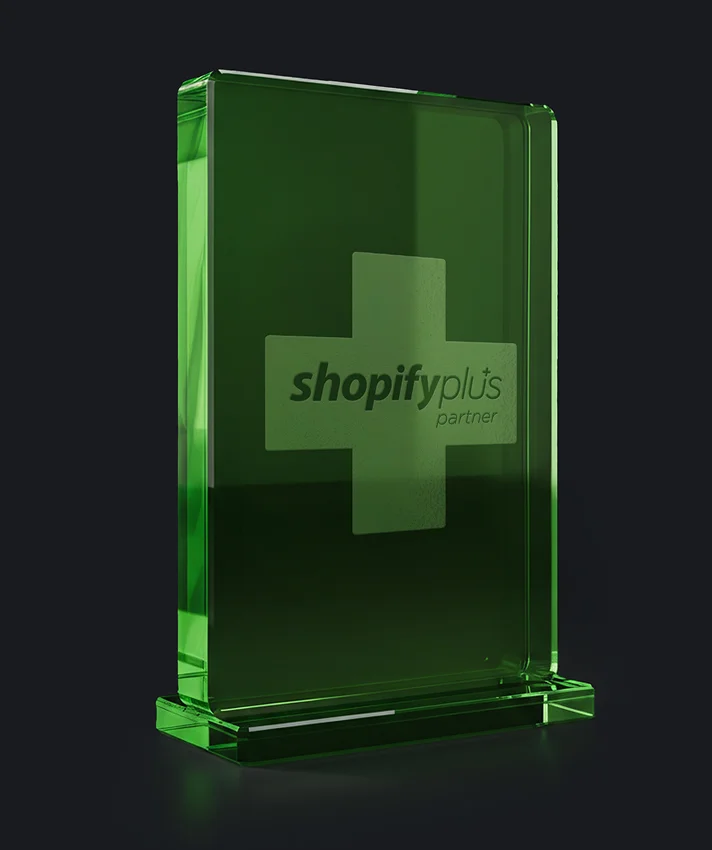 Shopify Plus Partner award trophy as a green glass block on a dark background