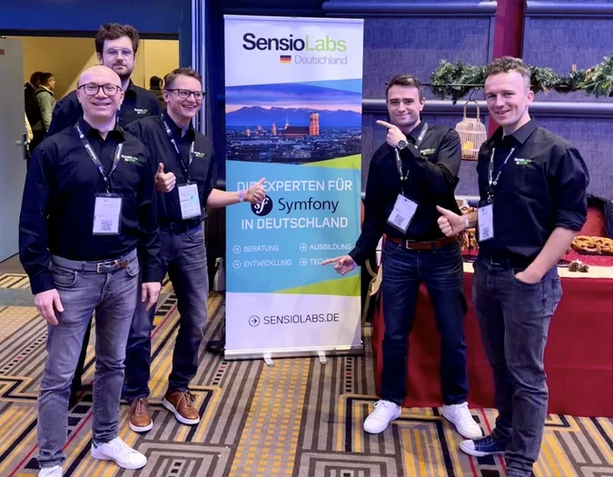 Five team members posing with a company banner
