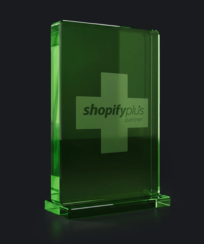 Shopify Plus Partner award trophy as a green glass block on a dark background