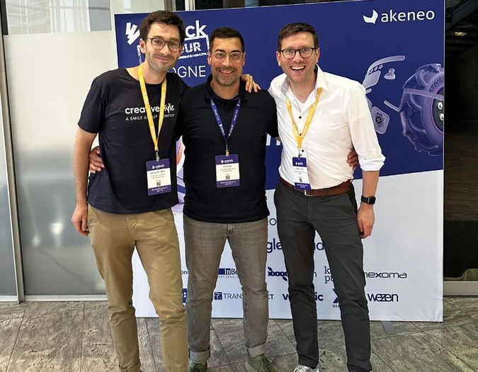 Three men posing in front of a blue Akeneo event banner