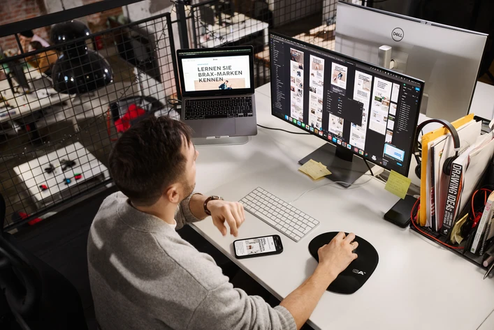 Designer reviewing interface layouts on dual-monitor workstation