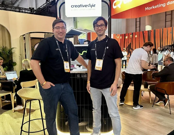 Two team members posing at a trade show booth with creative style branding during OMR Festival