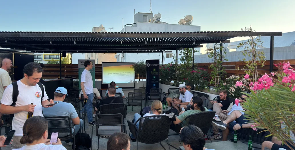 Outdoor rooftop presentation with a projector screen showing a Symfony technical slide