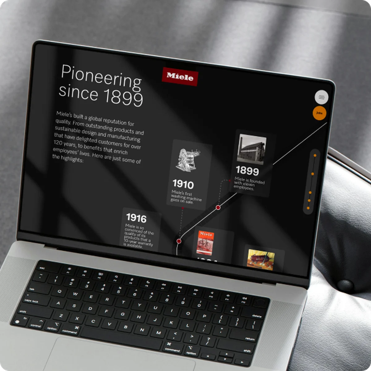 Miele X e-commerce website preview on a laptop showcasing a "Pioneering since 1899" brand history timeline, featuring milestones like the first washing machine from 1910, set against a dark background in a premium interior setting